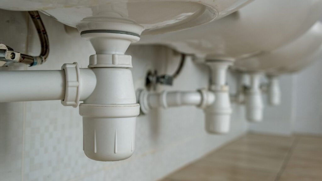 Close-up of white plastic sink drain pipes under a basin