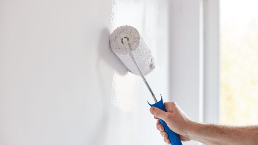 Hand painting a wall white with a paint roller