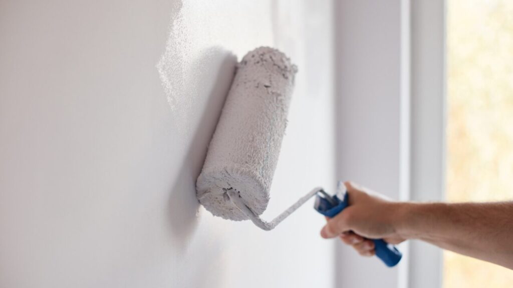 Hand painting a wall with a roller during apartment renovation