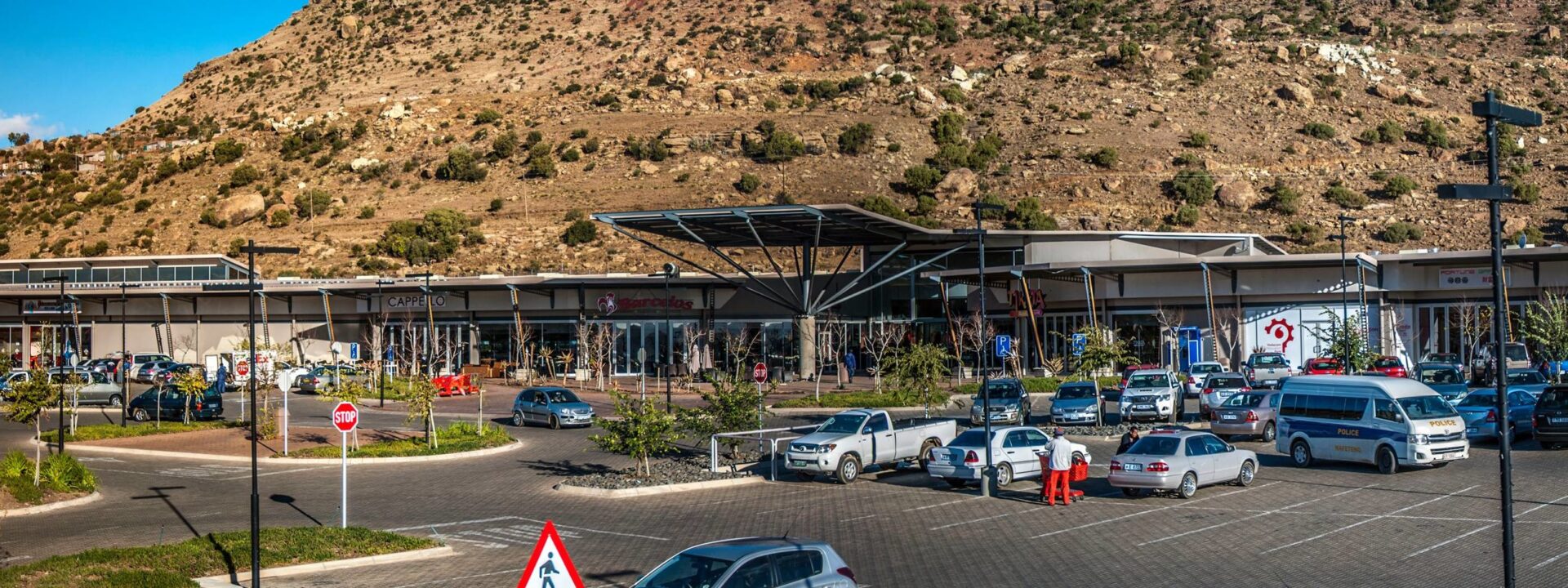 Exterior view of Maseru Mall with parked cars and hillside backdrop
