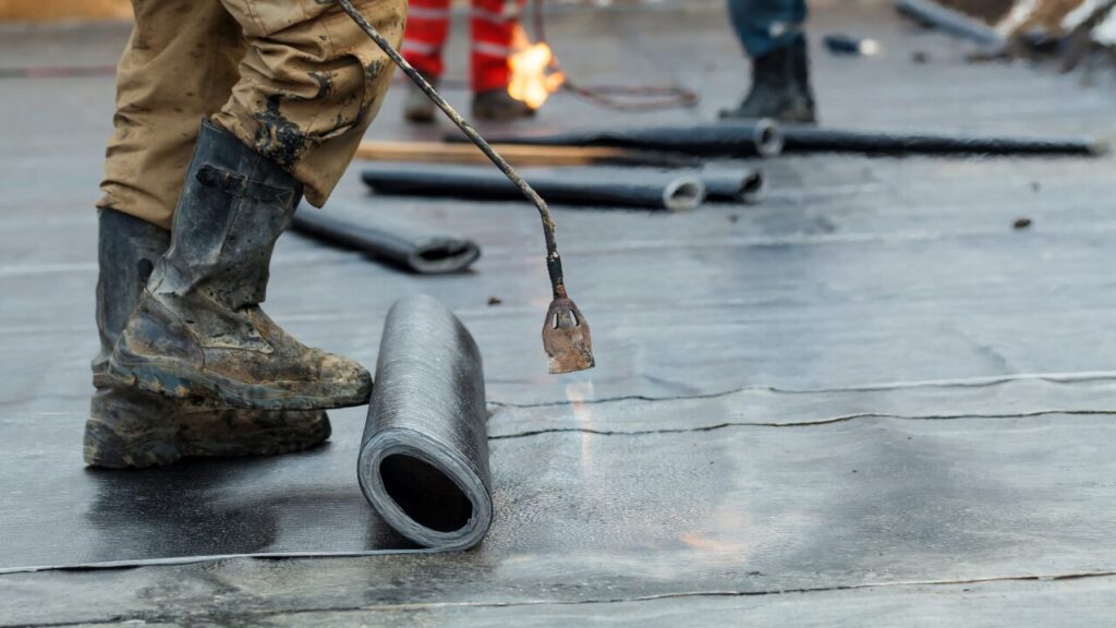 Worker applying waterproofing to a building foundation